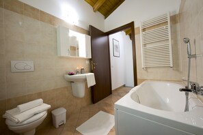Une salle de bain équipée d’une baignoire, de toilettes, d’un lavabo et d’un petit marchepied.