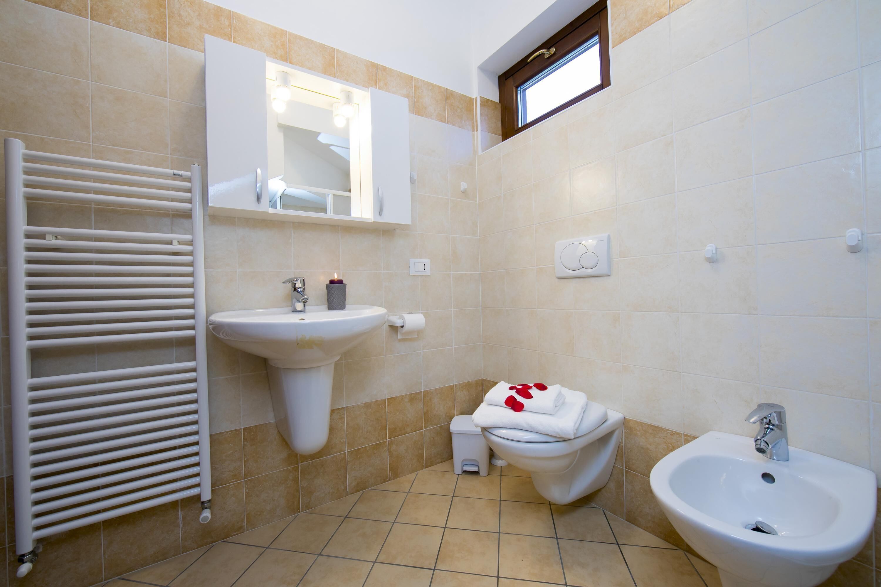 Une salle de bain avec un lavabo blanc, un bidet, un porte-serviettes et un miroir au-dessus du lavabo.