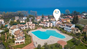 Vue aérienne d’un quartier résidentiel avec une grande piscine entourée de maisons.
