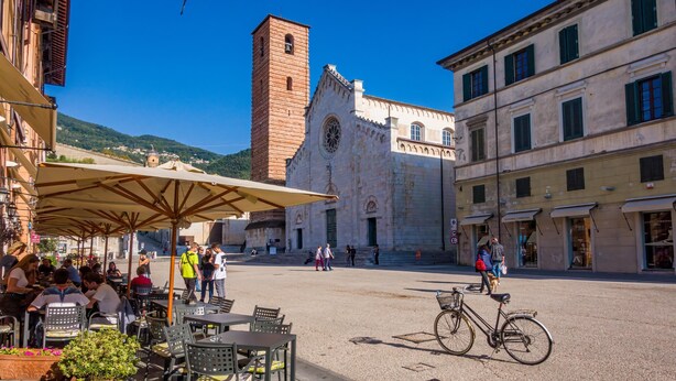 An outdoor café with tables and chairs, a bicycle, and a historic building in the background. - La Casina Del Pescatore On the Beach (Pietrasanta)