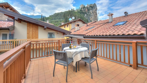 A balcony with a table and chairs, overlooking a mountainous landscape with a castle-like structure. - Arco Rocks 3 in Arco (Arco)