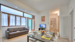A modern living room with a sofa, dining table, and TV. - Arco Rocks 1 in Arco (Arco)
