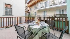 A balcony with a table set for dining, surrounded by metal chairs. - Arco Rocks 1 in Arco (Arco)
