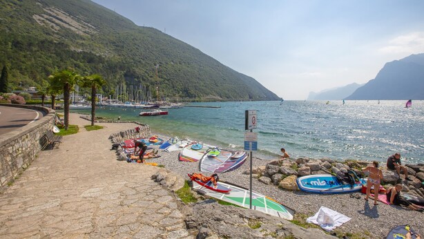 A coastal area with boats, a stone pathway, and a mountainous backdrop. - Casa dei Nonni in Arco (Arco)