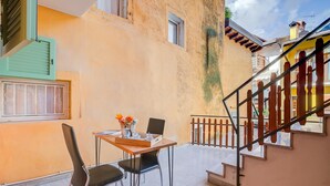 A small dining area with a table, chairs, and a window with shutters. - Casa dei Nonni in Arco (Arco)
