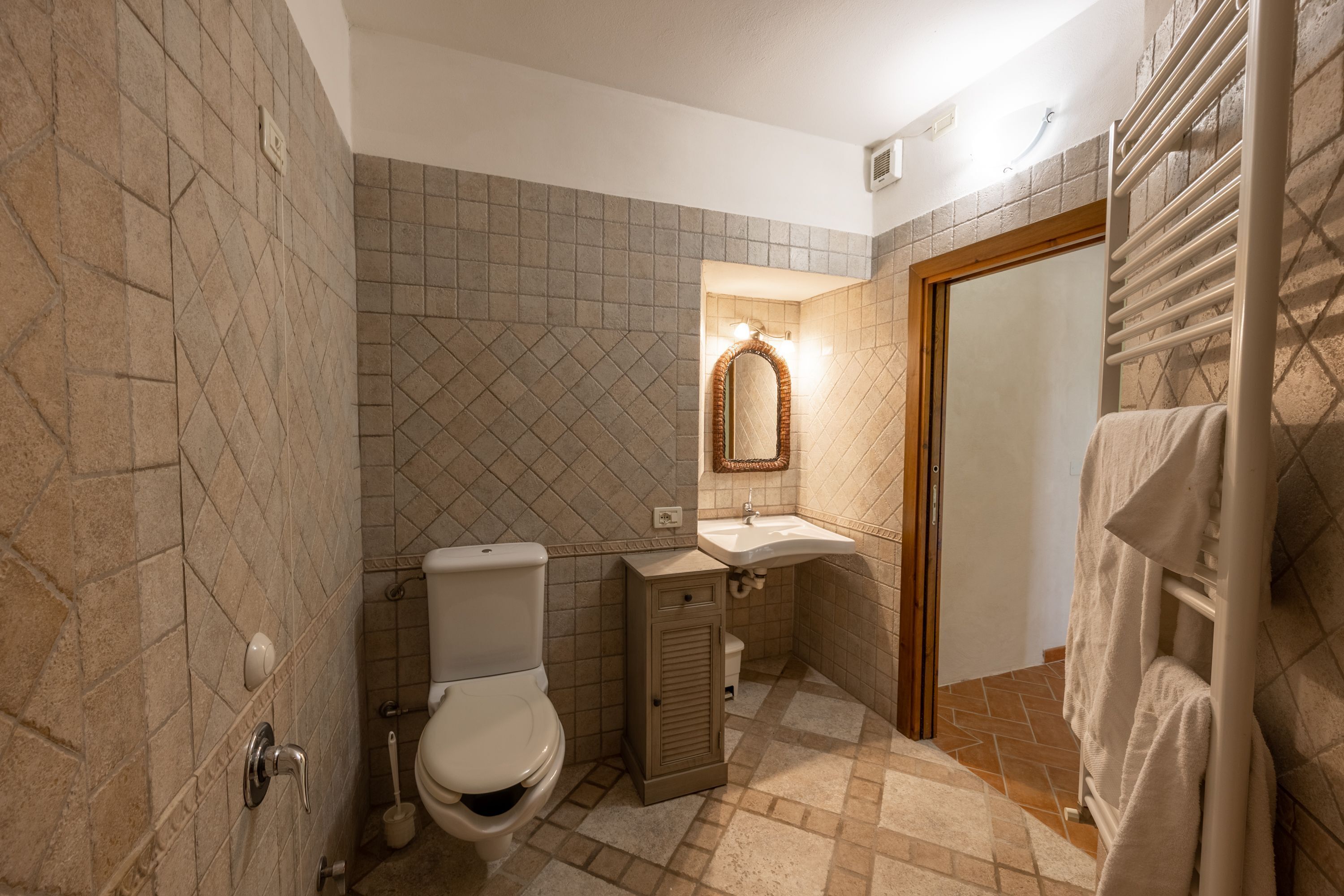 A bathroom with a toilet, sink, and towel rack.
