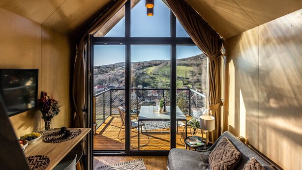 Une pièce chaleureuse avec une grande fenêtre, un plafond en bois et une vue sur la campagne.