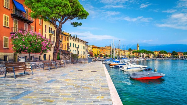 A waterfront promenade with stone pavement, benches, and boats docked along the water. - Margherita Near Lake-child Friendly (Toscolano Maderno)