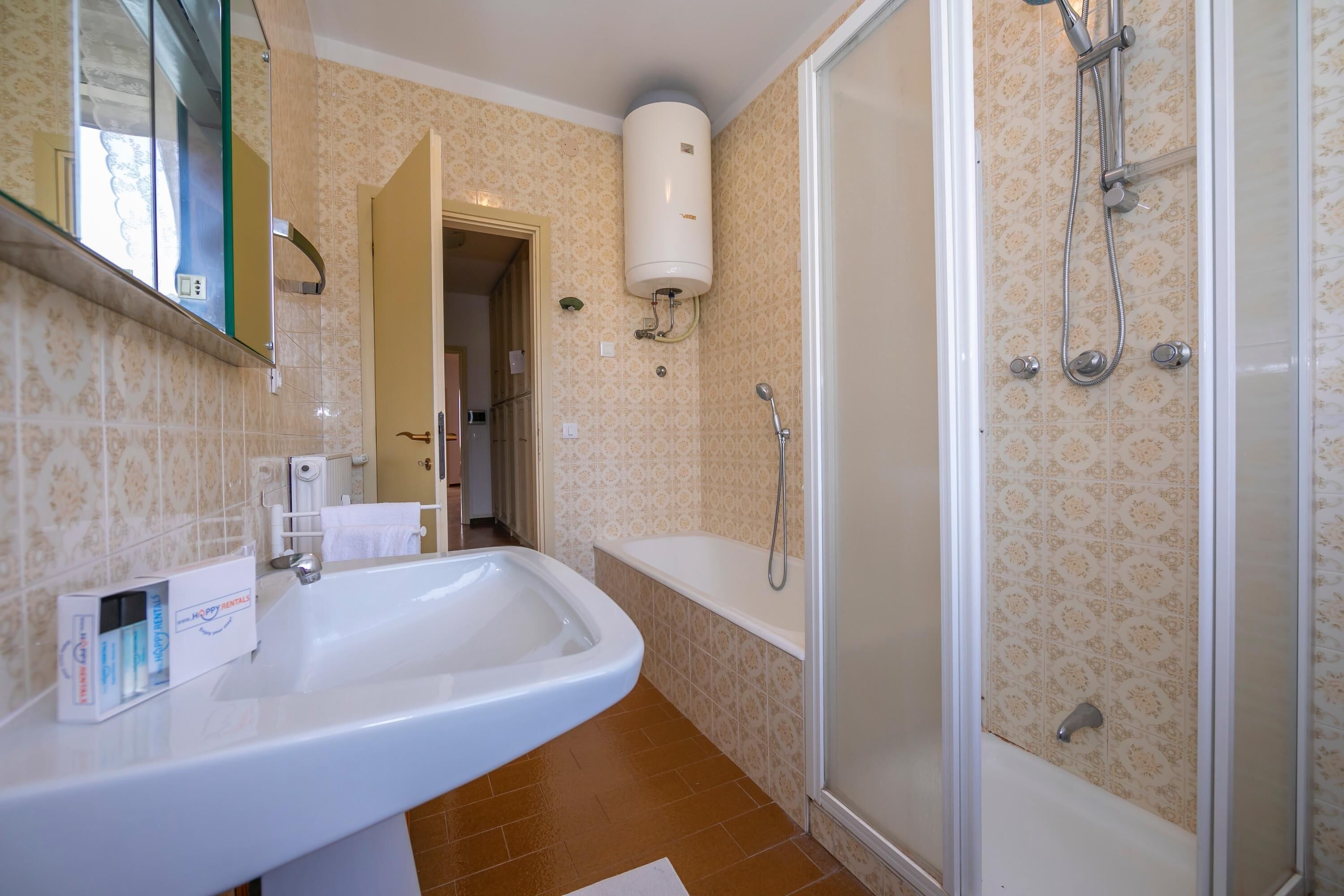 A bathroom with a white sink, a shower with a glass door, and a toilet.