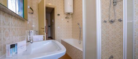 A bathroom with a white sink, a shower with a glass door, and a toilet.