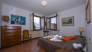 Un dormitorio con cama, cómoda, silla y obras de arte en las paredes.
