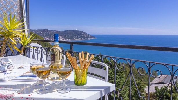 Une table avec des verres à vin et une bouteille, donnant sur une vue de la côte.