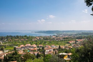 A coastal town with terracotta-roofed buildings, a clear blue sky, and a view of the sea.
