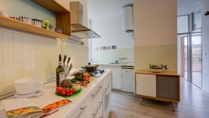 A modern kitchen with white cabinets, a wooden countertop, and a built-in stove. - Appartamento di Tommaso (Desenzano del Garda)