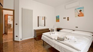 A hotel room with a large bed, a bedside table, a mirror, and a radiator. - Albatros in Dro With 2 Bedrooms and 1 Bathrooms (Dro)