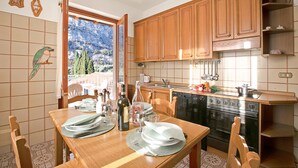 A kitchen with wooden cabinets, a dining table set with plates, glasses, and a bottle. - Albatros in Dro With 2 Bedrooms and 1 Bathrooms (Dro)