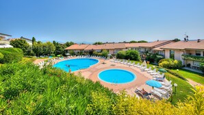 A resort with a large swimming pool, sun loungers, and a well-maintained garden. - Kristall Lago Pool View (Desenzano del Garda)