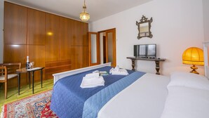 Ein Hotelzimmer mit Bett, Schreibtisch, Stuhl, Kleiderschrank, Spiegel und Lampe.