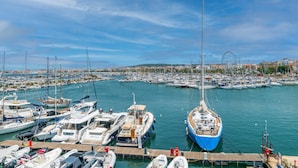 A marina with various boats docked, a Ferris wheel in the background, and a cityscape across the water. - Bilocale Vista Mare Giorgio (Alghero)