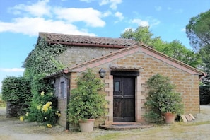 A small stone building with a tiled roof, a wooden door, and potted plants. - Casale Montemoro With Pool (Allerona)