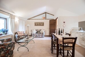 A living room with a sofa, chairs, a dining table, and a kitchen area with cabinets and a countertop. - Casale Montemoro With Pool (Allerona)