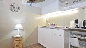 Un angolo cottura attrezzato con lavello, una sveglia, una lampada e una dispensa.