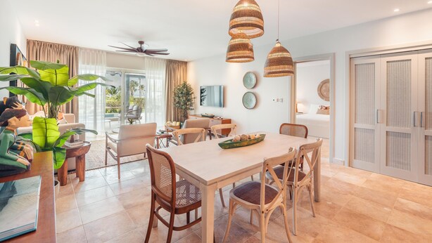 A spacious dining area with a wooden table and chairs, surrounded by a modern kitchen and a large window. - Apartment w Pool Ocean View at Punta Palmera BA5 (Punta Cana)