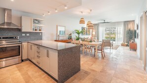 A modern kitchen with granite countertops, stainless steel appliances, and a dining area with a table and chairs. - Apartment w Pool Ocean View at Punta Palmera BA5 (Punta Cana)