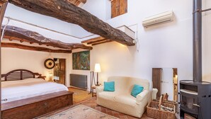 Ein gemütliches Zimmer mit einem Bett, einer Couch, einem Kamin und einer rustikalen Holzbalkendecke.