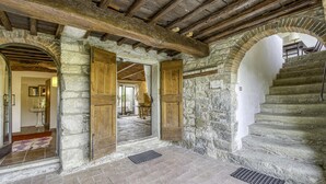 Ein Innenraum mit Steinwänden, Holztüren und einer Treppe.