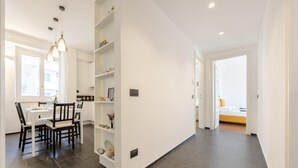 A modern interior with a dining area, a built-in bookshelf, and a bedroom with a bed and a window. - Charming Flat Sestri Levante (Sestri Levante)