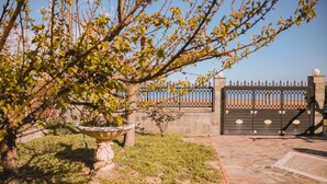 A garden with a stone fountain, a metal gate, and a paved walkway. - Villa Olga Sea Front Katakolo (Pyrgos)