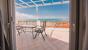 An open patio with a table and chairs, a view of the ocean, and a metal railing. - Villa Olga Sea Front Katakolo (Pyrgos)