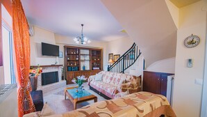 A living room with a fireplace, sofa, coffee table, and a staircase leading to another level. - Villa Olga Sea Front Katakolo (Pyrgos)