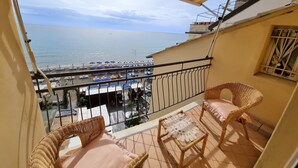 A balcony with wicker furniture, a view of the sea, and a parking area with umbrellas. - Il Bijou Di Rossella - Beach Front (Alassio)