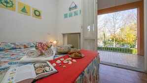 A room with a bed, a table with a book and pastries, a view of the outside, and a sign on the wall. - Casa Lavanda Pool Tennis (Ispra)