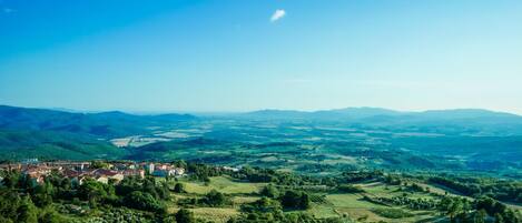 Vista panorámica de un pueblo situado en un valle con colinas onduladas y un cielo azul despejado.