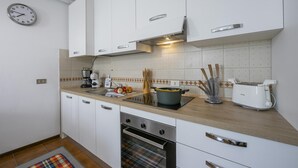Een moderne keuken met witte kasten, een inbouwoven, een magnetron en een broodrooster.