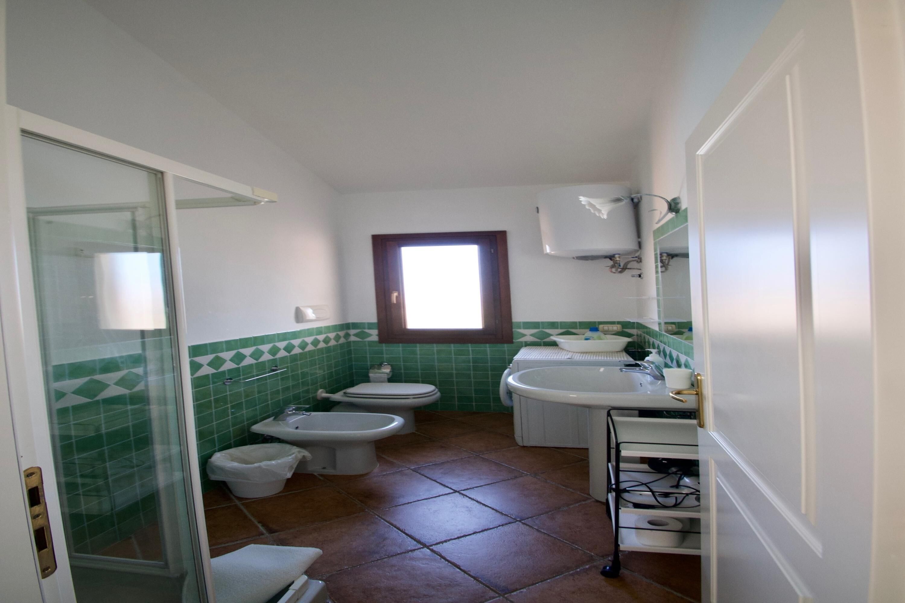 A bathroom with a shower, toilet, bidet, and sink.