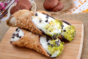 Two cannoli with chocolate chips and pistachio on a wooden board. - Casa Smeralda a 200 mt Dal Mare (Augusta)
