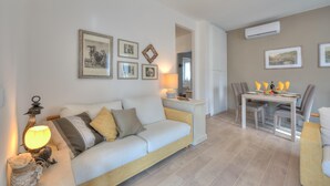 Ein modernes Wohnzimmer mit einer Couch, einem Esstisch mit Stühlen und einer Lampe.