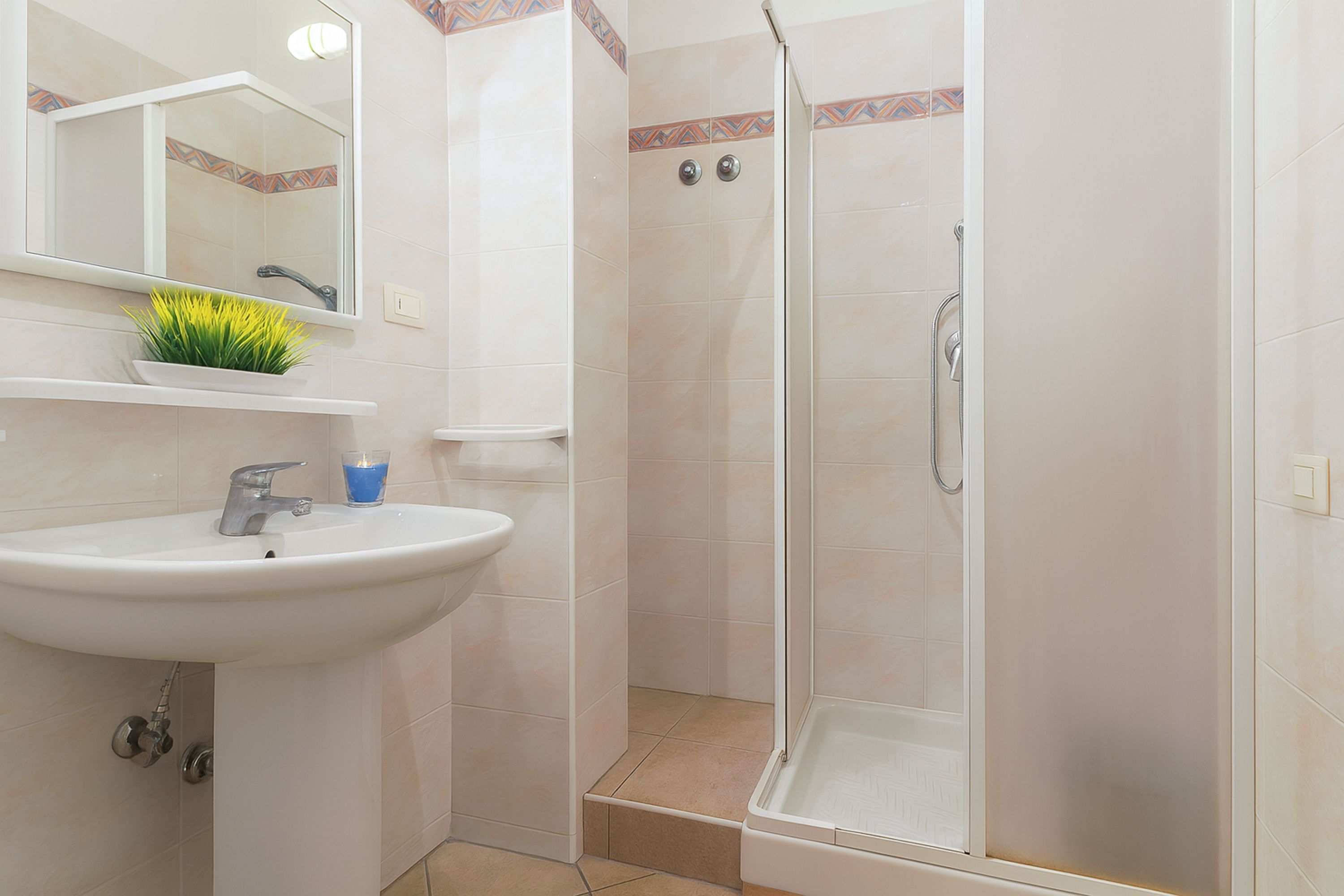 Een badkamer met een wastafel, spiegel en douche.