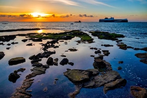A coastal scene with a sunset, rocky shoreline, and a large ship in the distance. - Daniela 4 100mt From sea (Massa)
