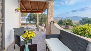 An outdoor patio with wicker furniture, a stone pillar, and a view of the landscape.