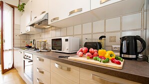 A modern kitchen with a microwave, toaster, and coffee maker. There is a cutting board with vegetables on the counter. - Appartamento Verona For You (Verona)