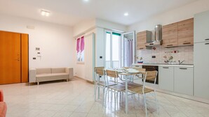 A modern kitchen with white cabinets, a stainless steel range hood, and a dining area with a white table and chairs. - House of the Gozzo in Monopoli (Monopoli)