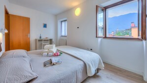 Une chambre à coucher avec un lit, une table de chevet, une fenêtre donnant sur la montagne et une porte.