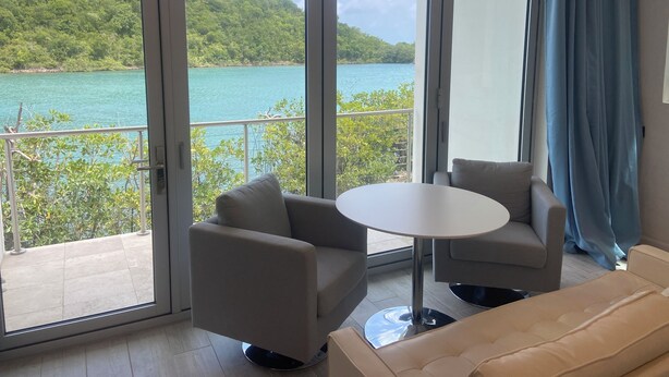 A modern room with a balcony, a round table, two armchairs, and a sofa.
