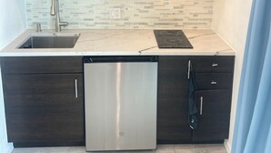A modern kitchen with dark wood cabinets, a stainless steel microwave, a dishwasher, and a tiled backsplash.