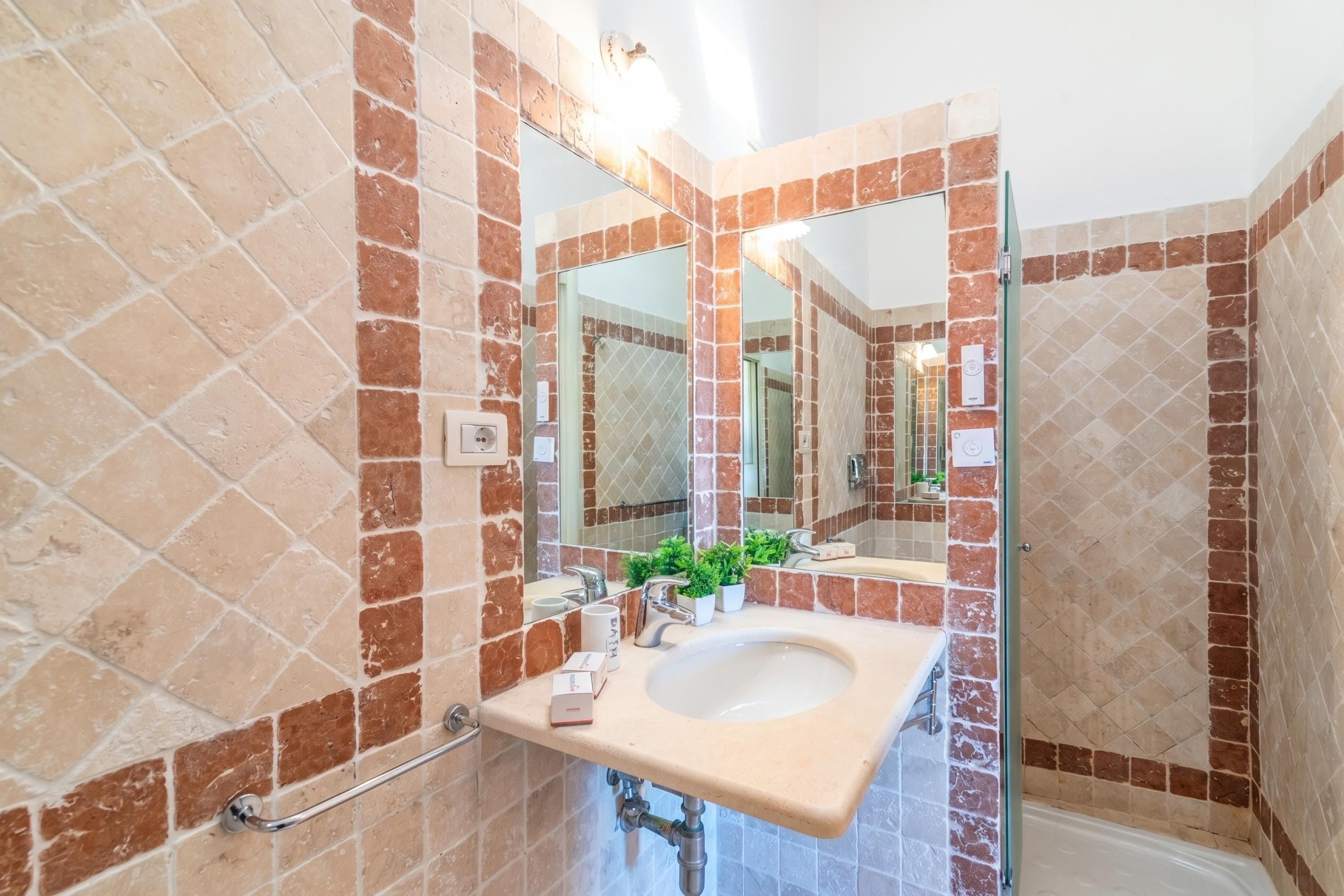 A bathroom with a sink, mirror, and shower.